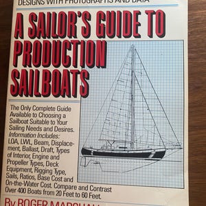 Peut inclure: Un livre intitulé "A Sailor's Guide to Production Sailboats" avec une illustration de voilier. La couverture présente du texte rouge et blanc, dont "More Than 400 Modern Production Sailboat Designs". Le livre fournit des données et des photographies.