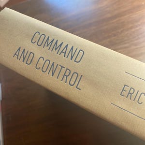 May include: Close-up of a brown book with the title "COMMAND AND CONTROL" and the author's name "ERIC" printed on the spine.