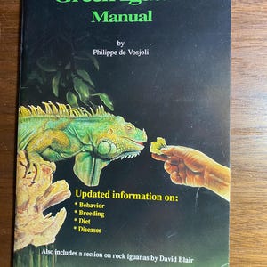 Puede incluir: La portada del libro "The Green Iguana Manual" presenta una ilustración de una iguana verde. El título está en verde, con el nombre del autor debajo. La portada también incluye información sobre comportamiento, reproducción, dieta y enfermedades. Edición especial.