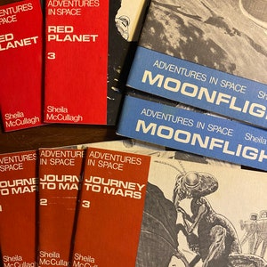 Op de afbeelding: Een verzameling rode en blauwe paperbacks met de titel "Adventures in Space" en verschillende ondertitels, waaronder "Red Planet", "Journey to Mars" en "Moonflight".