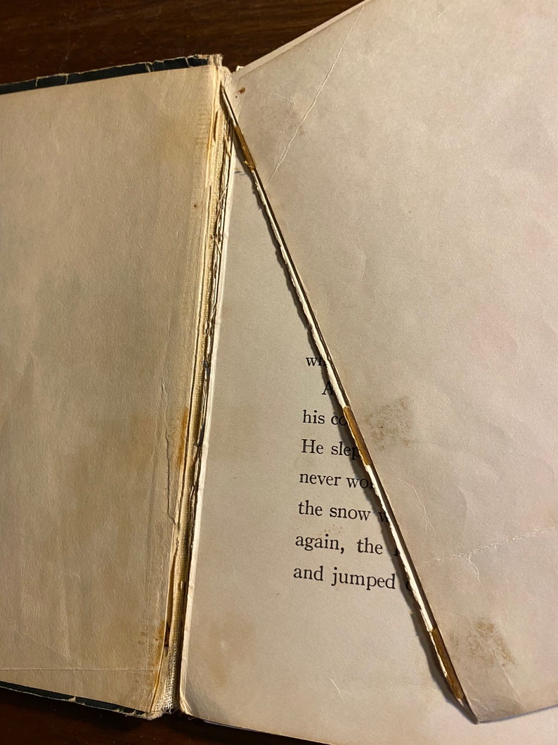 K&ouml;nnte beinhalten: Nahaufnahme eines Buches mit einer zerrissenen Seite. Der Text auf der Seite lautet: "his cold He slept never woke the snow again, the and jumped"