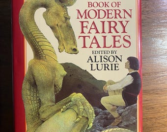Puede incluir: El libro Oxford de cuentos de hadas modernos, editado por Alison Lurie. La portada del libro presenta una criatura verde con forma de dragón y una figura sentada. El título está en letras rojas sobre un fondo crema, enmarcado por un borde rojo.