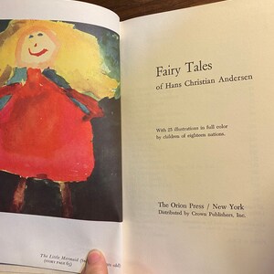 May include: A book titled "Fairy Tales of Hans Christian Andersen" with a colorful illustration of a girl in a red dress on the cover. The book is published by The Orion Press and distributed by Crown Publishers.