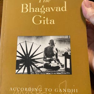 May include: A hardcover book titled "The Bhagavad Gita" with the subtitle "According to Gandhi." The cover is a mustard yellow color with the title in gold lettering. A black and white image of Gandhi is in the center.