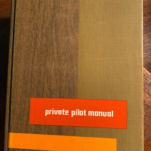 May include: A brown and green book with the title "private pilot manual" in red lettering on a red background. The book has a white "S" logo with the word "SANDERSON" below it.