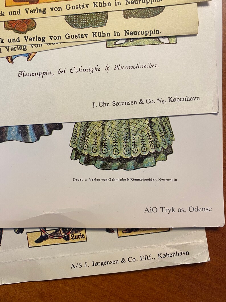 May include: A vintage paper doll with a green and white dress. The doll is from a book published by Gustav K&uuml;hn in Neuruppin, Germany. The text on the page reads "Druck u Verlag von Oehmigke & Riemschneider, Neuruppin".