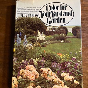 Puede incluir: Portada de libro con el título "Color for Your Yard and Garden" en un círculo. La portada presenta una fotografía de un jardín con una variedad de flores en flor, incluyendo rosas rosas, flores moradas y follaje verde.
