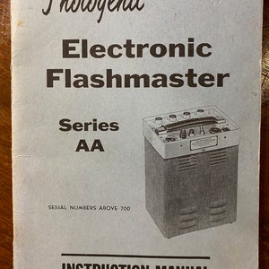 Pode incluir: Um manual de instruções em preto e branco para o Photogenic Electronic Flashmaster Série AA. O manual tem o texto "Instruction Manual and Parts List" na capa. O manual é para números de série acima de 700.