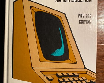 Op de afbeelding: Een vintage boekomslag met een gele en bruine illustratie van een computer. De titel is "Computers in Business Management: An Introduction, Revised Edition" door James A. O'Brien.