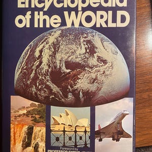 May include: The cover of a book titled "The NEW Encyclopedia of the WORLD". The cover features a colorful image of the Earth, a waterfall, the Sydney Opera House, and a Concorde supersonic jet.