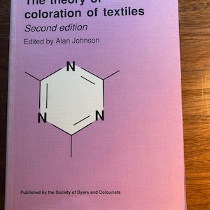 May include: A book titled "The theory of coloration of textiles, Second edition" edited by Alan Johnson. The cover is light purple with a white and black chemical structure graphic. Published by the Society of Dyers and Colourists.