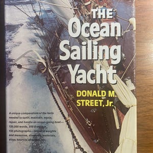 Puede incluir: La portada del libro "The Ocean Sailing Yacht" de Donald M. Street, Jr. La imagen muestra un velero en el mar con velas blancas y un casco de madera. La portada del libro también incluye texto que describe el contenido.