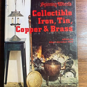 May include: A book cover titled "Spinning Wheel's Collectible Iron, Tin, Copper & Brass" with a vintage illustration. The cover features a black background with red text and an image of antique metal objects, including a lamp and a kettle.