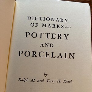 May include: Open book page with the title "DICTIONARY OF MARKS ~ POTTERY AND PORCELAIN" in black text. The authors are Ralph M. and Terry H. Kovel. The publisher is Crown Publishers, Inc., New York.