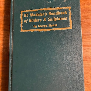 May include: A green hardcover book with a gold title that reads "RC Modeler's Handbook of Gliders & Sailplanes By George Siposs".