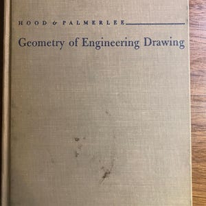 May include: A hardback book titled "Geometry of Engineering Drawing" by Hood & Palmerlee. The cover is a light tan colour with some dark marks. The book is set against a wooden surface.
