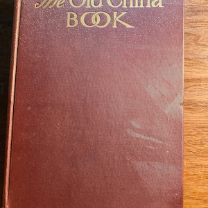 Puede incluir: Un libro de color burdeos con el título "The Old China Book" en letras doradas.