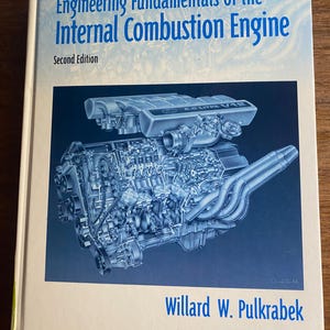 Op de afbeelding: Een gebonden leerboek getiteld Engineering Fundamentals of the Internal Combustion Engine, Second Edition door Willard W. Pulkrabek. De kaft bevat een blauw-witte illustratie van een 6.0 liter V12-motor tegen een donkerblauwe achtergrond.