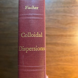 May include: A burgundy book with gold lettering on the spine. The title is "Fischer Colloidal Dispersions" and the publisher is "Wiley".