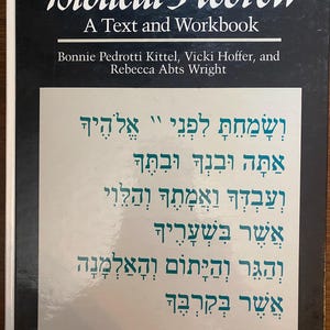 Puede incluir: Un libro de texto titulado "Biblical Hebrew: A Text and Workbook" con los nombres de los autores. La portada es negra con texto blanco en la parte superior y un panel verde claro con texto hebreo.