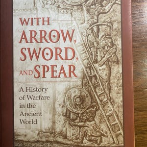 May include: A hardcover book titled "With Arrow, Sword, and Spear" by Alfred S. Bradford, illustrated by Pamela M. Bradford. The cover features a detailed illustration of ancient warfare, with figures, shields, and a ladder. The title is in large, red letters.