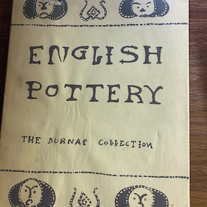 May include: A tan-colored book cover titled English Pottery The Burnap Collection in black lettering. The cover features black decorative borders with stylized face illustrations and abstract symbols at the top and bottom edges, with visible wear.
