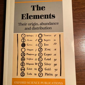 Puede incluir: Una portada de libro con el título "The Elements" de P.A. Cox. La portada presenta una tabla de elementos con sus símbolos y números atómicos, junto con su abundancia en la corteza terrestre.