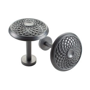May include: Two gray metal curtain tiebacks. Each tieback features a circular, decorative head with an intricate geometric pattern. The tiebacks have a stem and a round base. The design is a classic, elegant style.