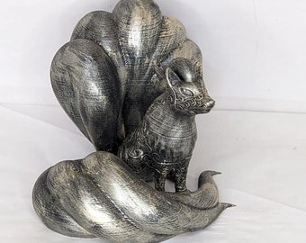 May include: A silver-colored figurine of a nine-tailed fox with intricate details. The fox is sitting with its tail curled around its body.