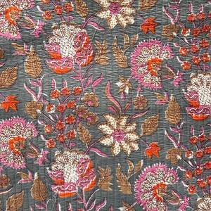 May include: A floral pattern on a gray background. The design features large flowers in shades of pink, orange, and white, with brown leaves and stems. The fabric has a quilted texture.