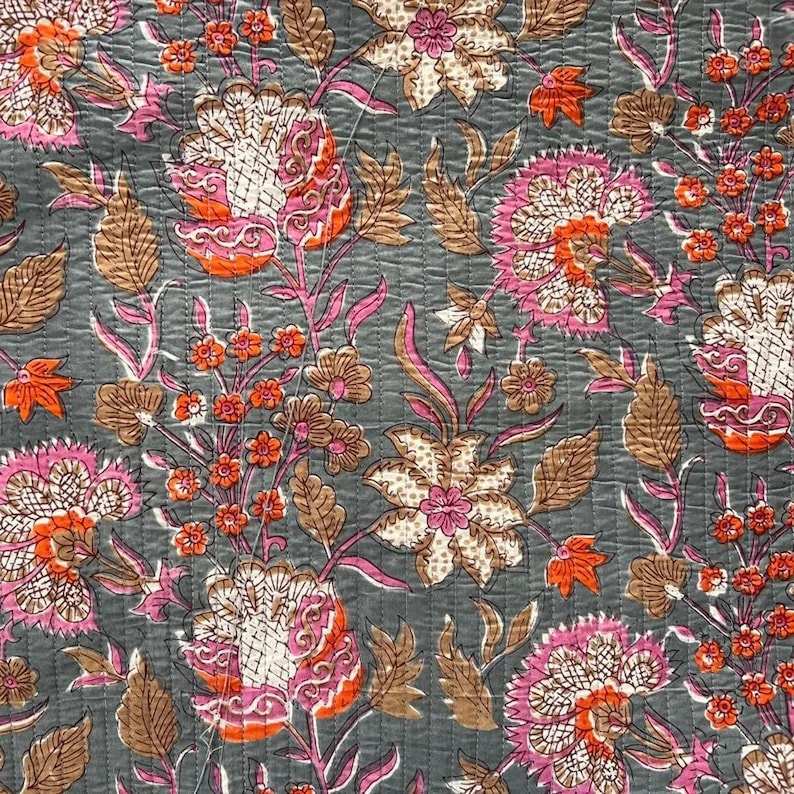 May include: A floral pattern on a gray background. The design features large flowers in shades of pink, orange, and white, with brown leaves and stems. The fabric has a quilted texture.