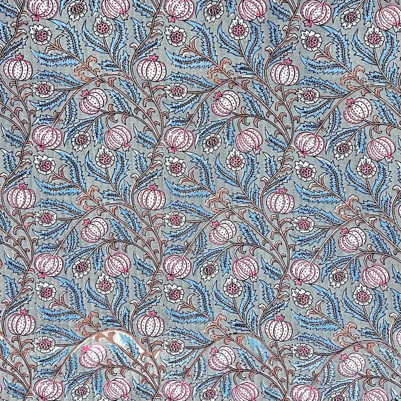 May include: A fabric textile featuring a repeating botanical pattern on a light gray background. The design consists of stylized pink and white pomegranate-like fruits and intricate blue serrated leaves connected by thin, dark brown winding vines.
