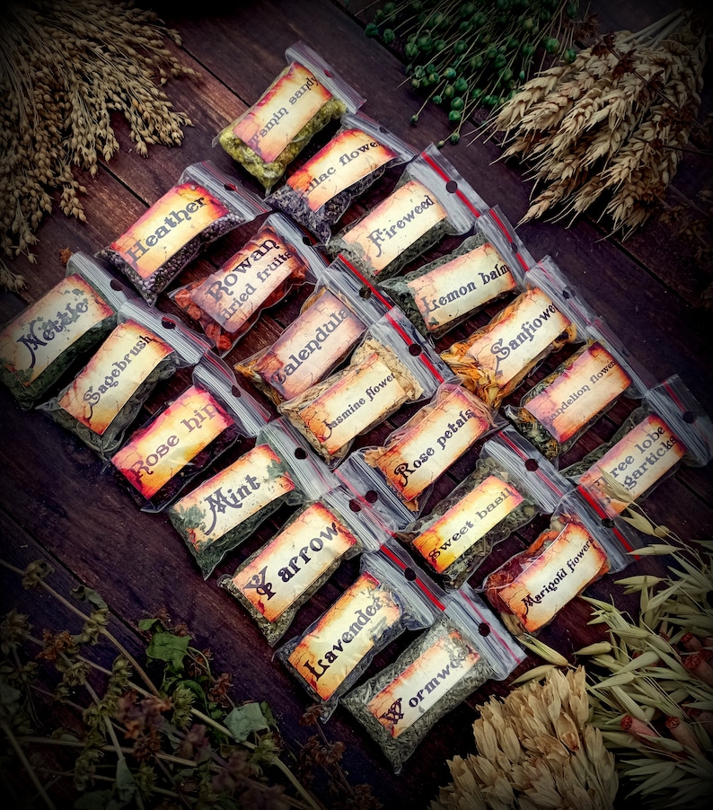 May include: A collection of small, clear plastic bags filled with dried herbs and flowers. Each bag has a handwritten label with the name of the herb or flower, such as "Mottle", "Heather", "Rowan dried fruits", "Fireweed", "Calendula", "Jasmine flower", "Rose petals", "Sweet basil", "Lemon balm", "Sanfiowe", "Dandelion flower", "Wormwoo", "Marigold flower", "ree lobe gartick", "Tamin sandy", "lac flowe", "Sagebrush", "Rose hip", "Mint", "arrow", "Lavender".