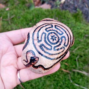 El símbolo de Hécate, una piedra marina dibujada sobre el familiar de la diosa, el Strófalo o Rueda de Hécate, servía para comunicarse con la diosa de la brujería.