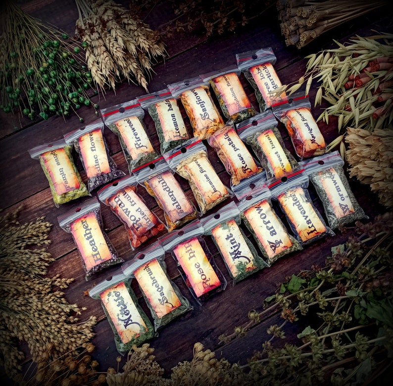 May include: A collection of small, clear plastic bags filled with dried herbs and flowers. The bags are labeled with the names of the herbs and flowers, such as "Lemon Balm", "Fireweed", "Heather", and "Rose Petals".