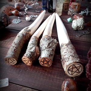 May include: Four wooden wands with a pentagram carved into the end of each. The wands are light brown and have a natural bark texture.