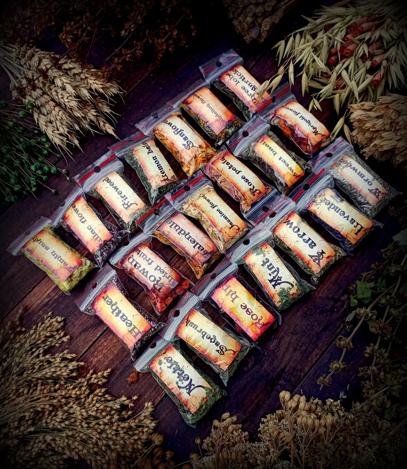May include: A collection of small, clear plastic bags filled with dried herbs and flowers. Each bag has a handwritten label with the name of the herb or flower, such as "Sagebrush", "Rose hip", "Mint", and "Lavender".