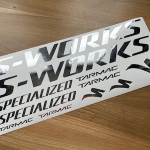 Könnte beinhalten: Ein Satz schwarzer und silberner Vinyl-Aufkleber mit den Worten "S-Works", "Specialized" und "Tarmac".