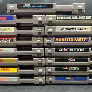 May include: A collection of grey video game cartridges with vibrant labels. Titles include "Kirby's Adventure," "Silver Surfer," "Metal Gear," "Double Dragon," "Dragon Warrior," "Metroid," "Super Mario Bros./Duck Hunt," "California Games," "Monster Party," and "Ghostbusters."