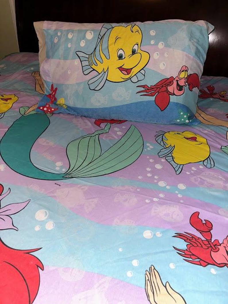 May include: A white ceramic mug with a black handle and the text "But First, Coffee" in a black, handwritten-style font. The mug is on a white surface.