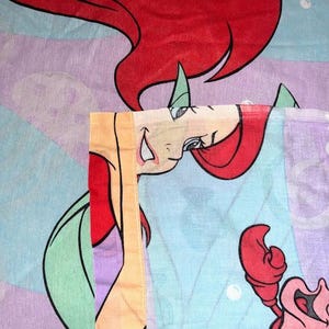 May include: A white ceramic mug with a black handle and the text "But First, Coffee" in a bold, black font. The mug is set against a blurred background, suggesting a cozy setting.