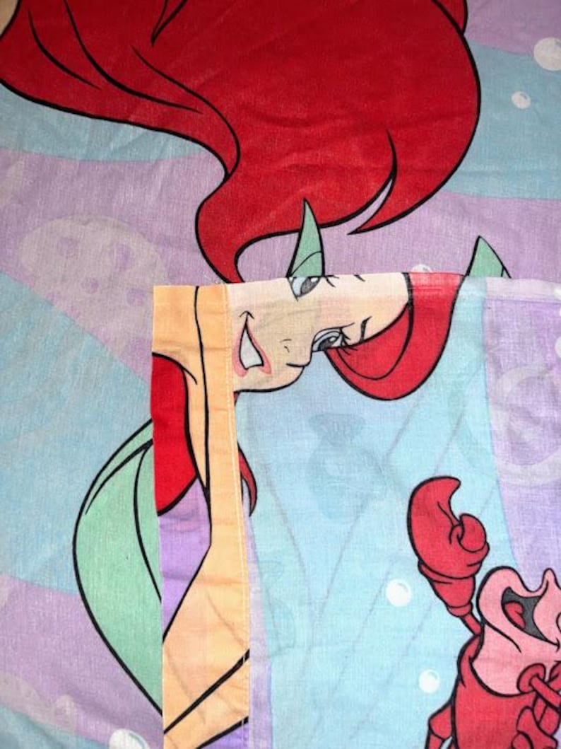 May include: A white ceramic mug with a black handle and the text "But First, Coffee" in a bold, black font. The mug is set against a blurred background, suggesting a cozy setting.