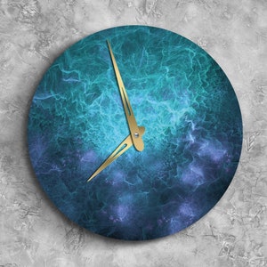 Puede incluir: Un reloj redondo con un diseño de mármol azul y morado. El reloj tiene manecillas doradas y un centro blanco.