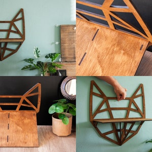 May include: A wooden fox-shaped shelf with a geometric design. The shelf is made of stained wood and has a natural finish. It is mounted on a wall and has a small shelf for displaying items.