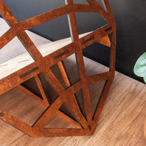 May include: A geometric wooden shelf with a brown wood finish. The shelf is made of multiple pieces of wood that are joined together to create a geometric pattern. The shelf is sitting on a wooden surface.