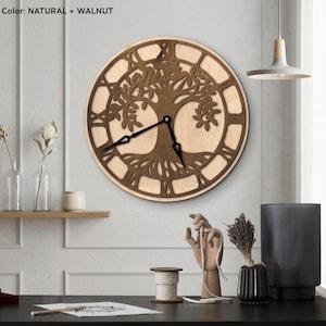 May include: A round wooden wall clock with a tree of life design. The clock features Roman numerals and black clock hands. The color is natural and walnut. The clock is mounted on a light-colored wall.