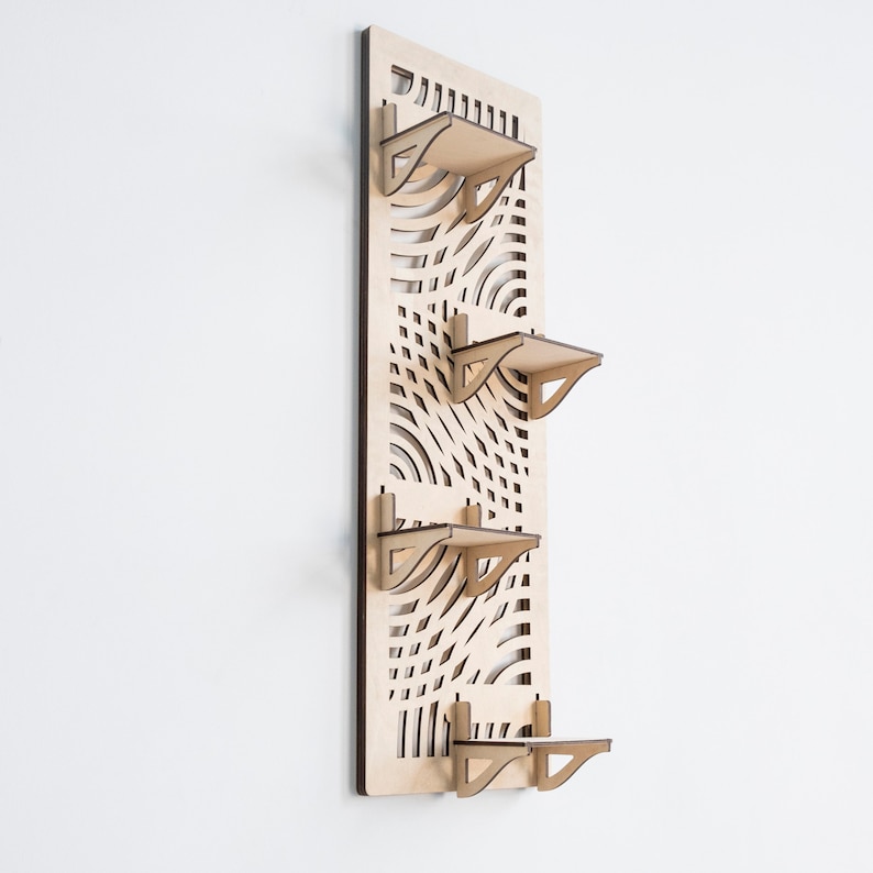 May include: A wooden wall shelf with a geometric pattern and four shelves. The shelves are made of light wood and have a simple design.