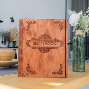 May include: A wooden recipe book with an engraved design and the words "RECIPE BOOK" on the front cover.