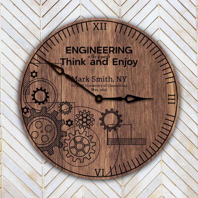 May include: A wooden clock with a brown background and black hands. The clock face has a design of gears and the text "ENGINEERING is like a puzzle Think and Enjoy Mark Smith, NY UCONN, University of Connecticut May, 2023".
