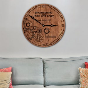 May include: A wooden clock with a gear design and the text "ENGINEERING is the art of Think and Enjoy". The clock also includes the text "Mark Smith, NY ICO University of Connecticut May 2023".